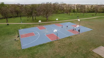 large basketball courts surrounded by grass and trails