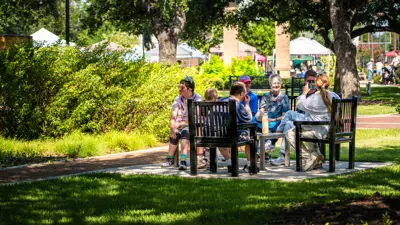 group of people sitting on benches in a park outdoors