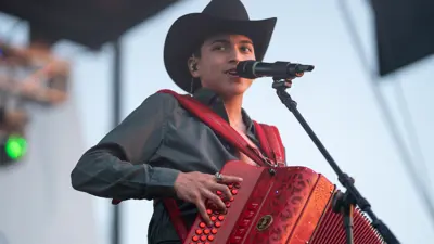 A young man plays the accordion while singing into a microphone at the Kyle Fair.