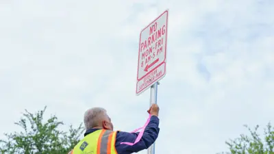 A picture of a City of Kyle employee taking a photo of a No Parking sign - May to September. 