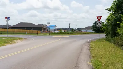 A photo of the intersection of Roland Lane and South Main Street in Kyle, Texas with a roundabout at the center. 