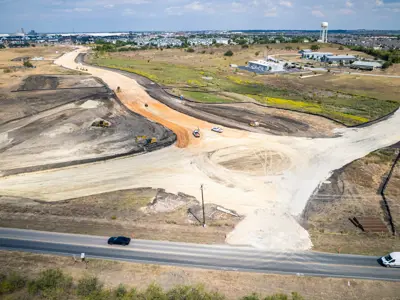 Drone picture of a roundabout in the early stages of construction at the Kohlers to Seton 2022 Road Bond projects. A circle of light brown dirt in a circle with four roadways leading out.