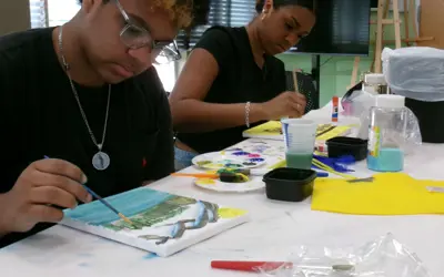 2 people use watercolor to paint on a canvas.