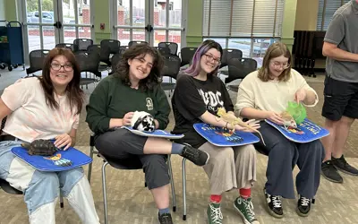 4 women sit in a row each holding a turtle, a rabbit, a lizard, and a hedgehog.