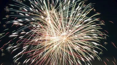 A photo of a large firework with red and white hues in the night sky. 