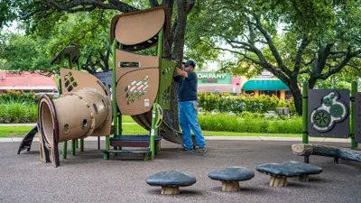 man working on nature themed playground equipment