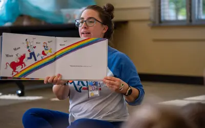 A woman reading a children's picture book.