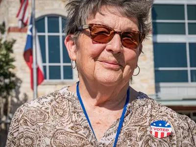A lady smiling and wearing an "I Voted" sticker