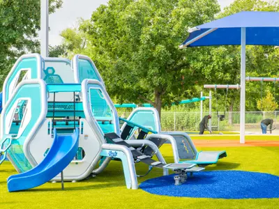 A picture of a bright blue and dark blue playground with hexagonal boxes sit on bright green turf with splashes of yellow.