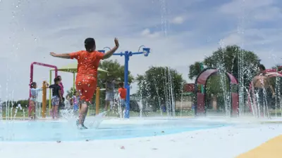 A photo of a child playing at the Gregg-Clarke Park Splash Pad on a sunny day with no clouds in the sky. 