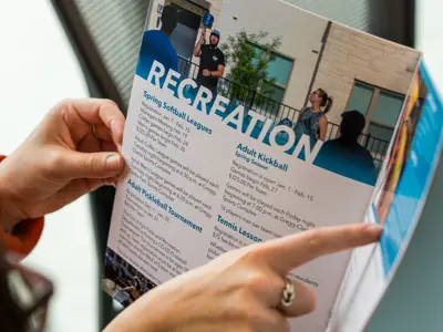 A picture of two people pointing out events and programs in the 2025 Parks and Recreation Winter Guide. 